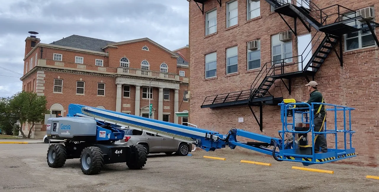 Boom lift raised beside a multi-story brick building for exterior work