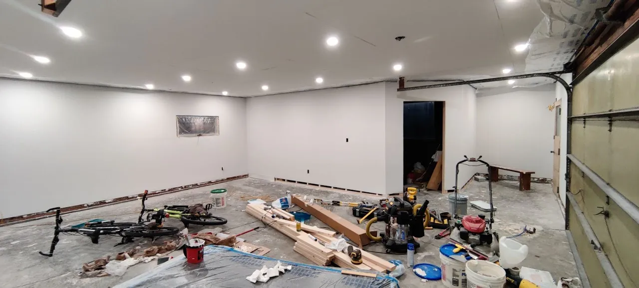 Garage interior finished with painted drywall and recessed lighting, trim staged on the floor